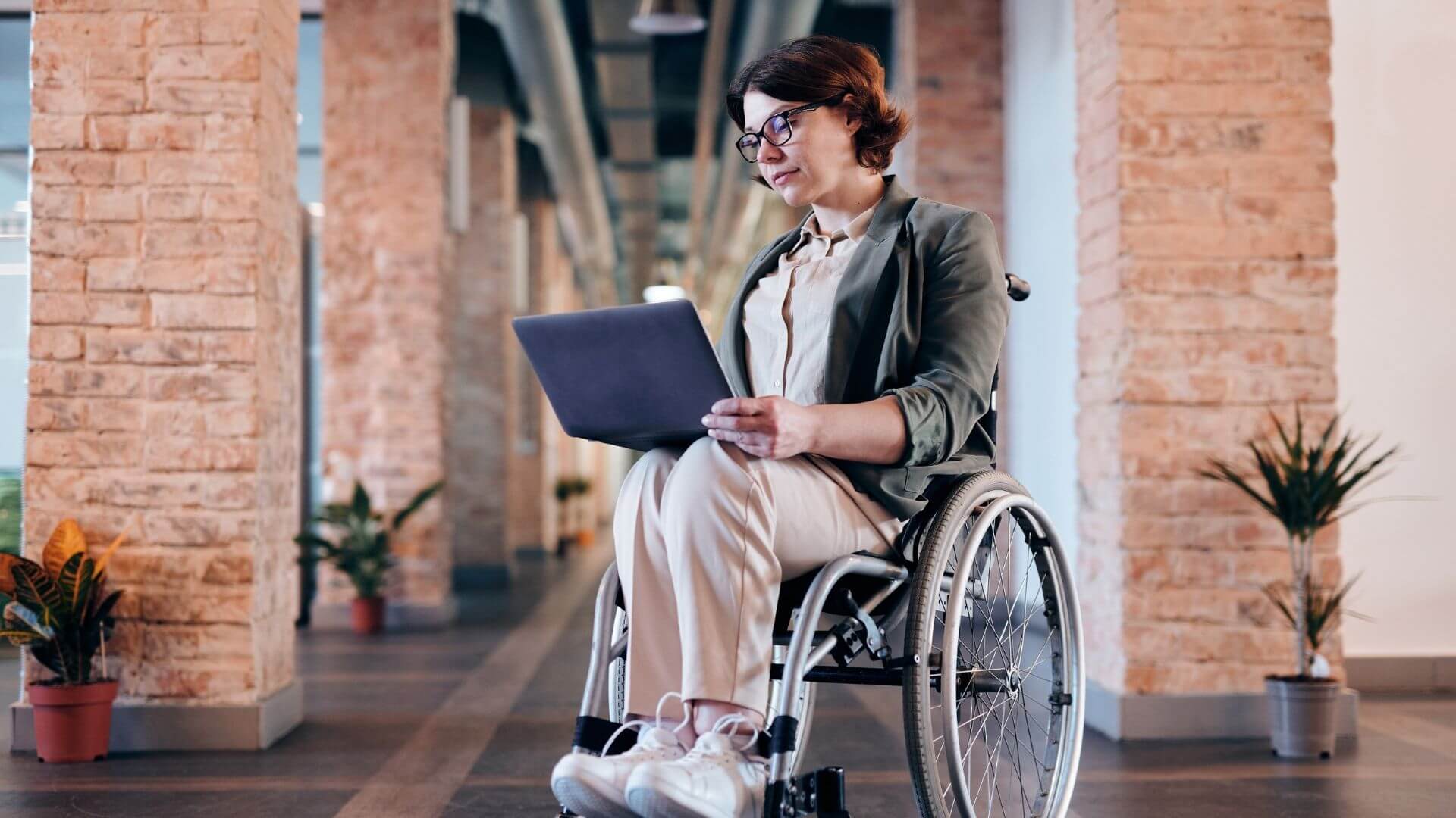 Personne en fauteuil roulant avec un ordinateur sur les jambes