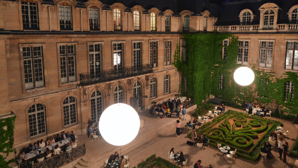 cour du château, de nuit, avec différents coins avec des tables et des chaises parmi le jardin à la française, c'est la deuxième idée de séminaire d'entreprise unique près de Paris
