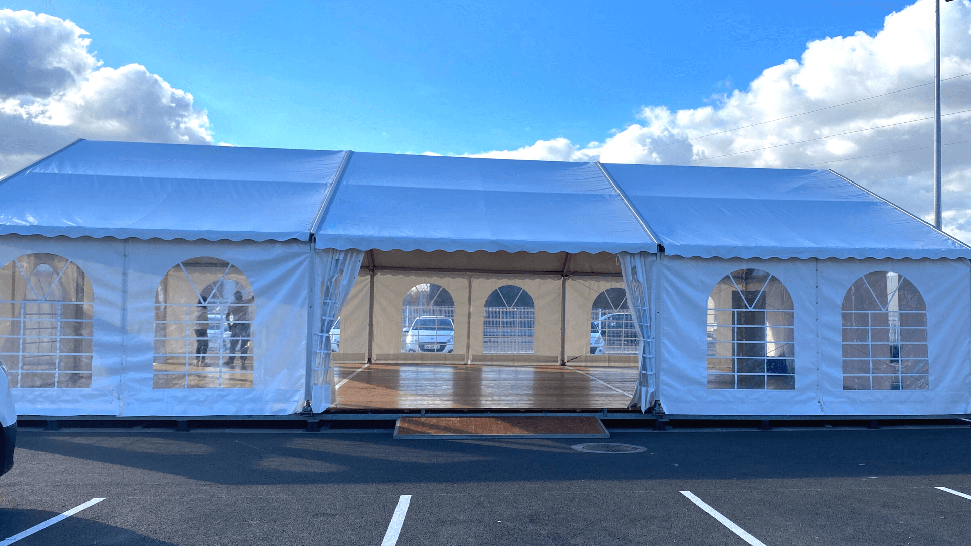 Grande tente blanche en extérieur, sur le parking de l'événement
