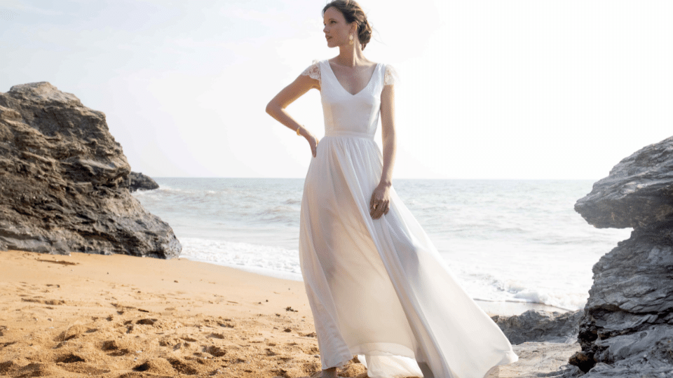 Robe de mariée écoresponsable. La mariée pose sur un rocher, sur la plage.