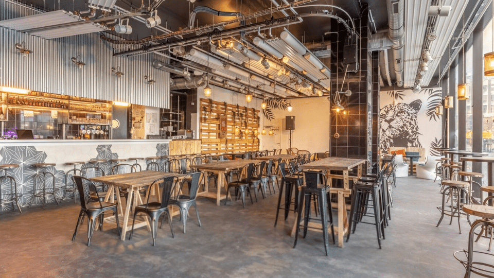 Grand lieu parisien pour événement pro ou personnel, avec des tables en bois et des chaises en métal façon loft industriel