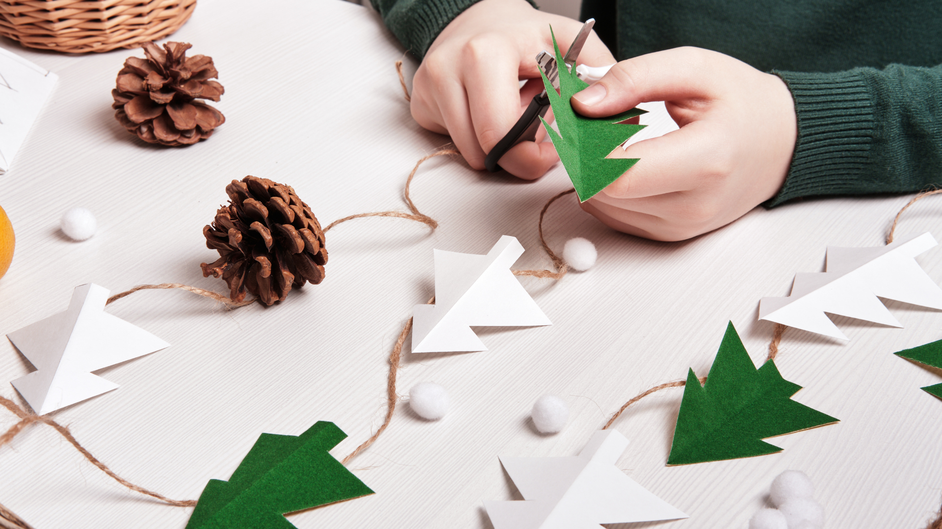Enfant réalisant une guirlande de sapins en papier